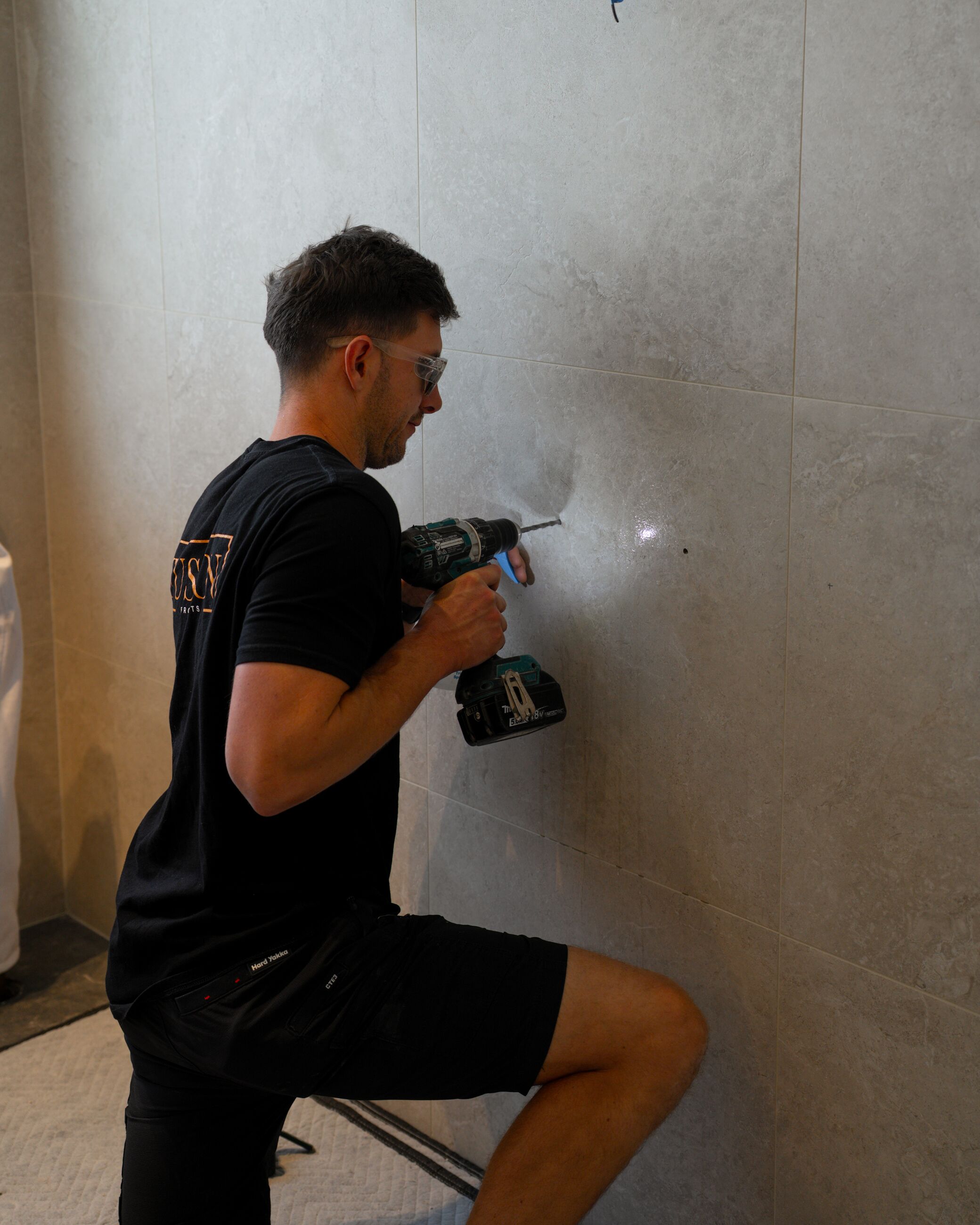 Fusion electrician drilling into a wall during an installation