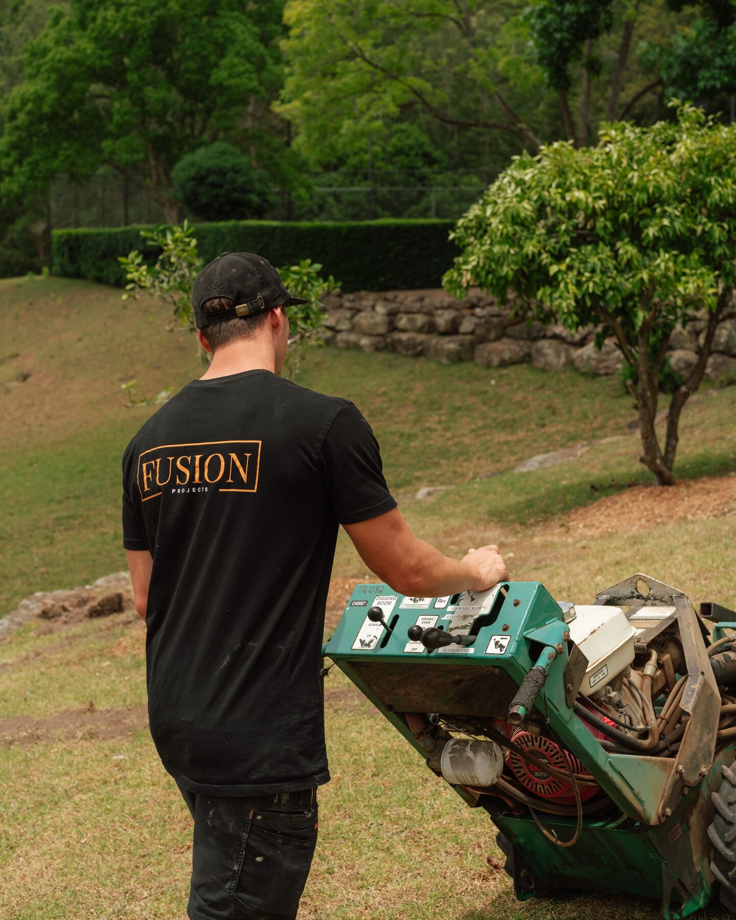 Fusion crew member cutting a cable trench across a lawn with a trencher