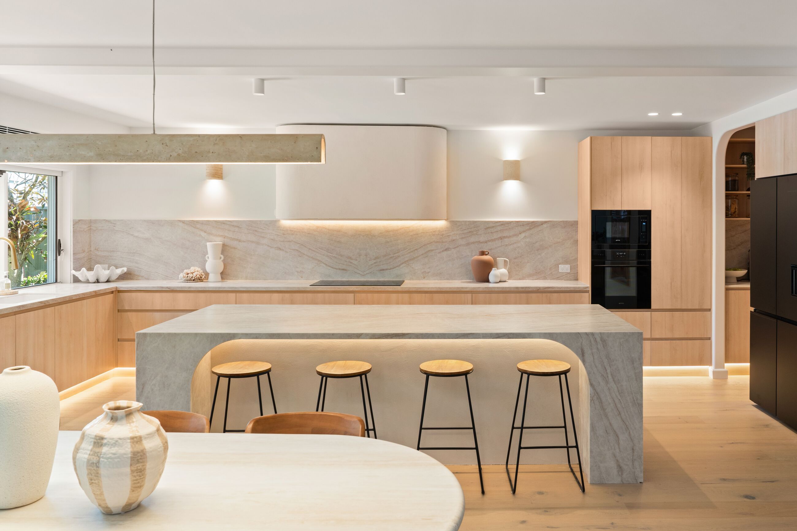 Open plan kitchen and dining area with downlights, track lights and a pendant