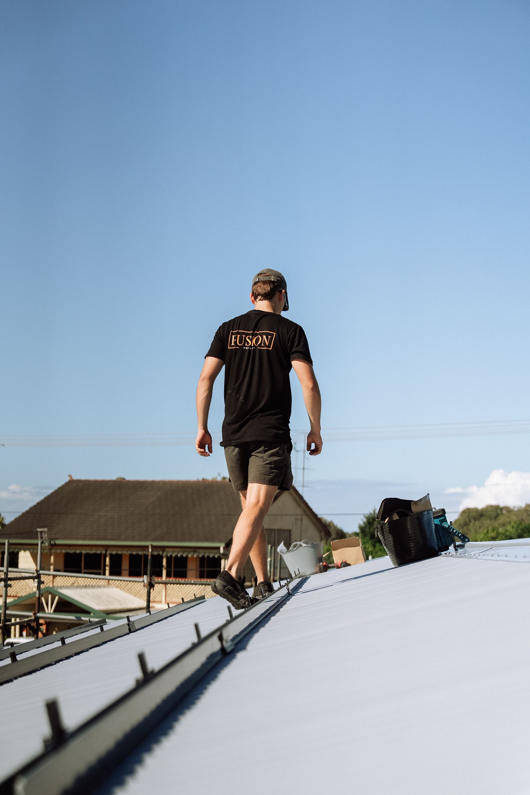 Fusion installer in a branded shirt walking across a metal roof
